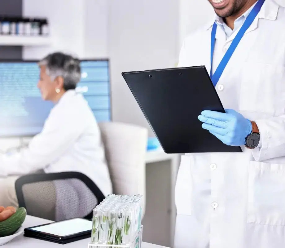 Un especialista de laboratorio con bata blanca sosteniendo un portapapeles durante la capacitación