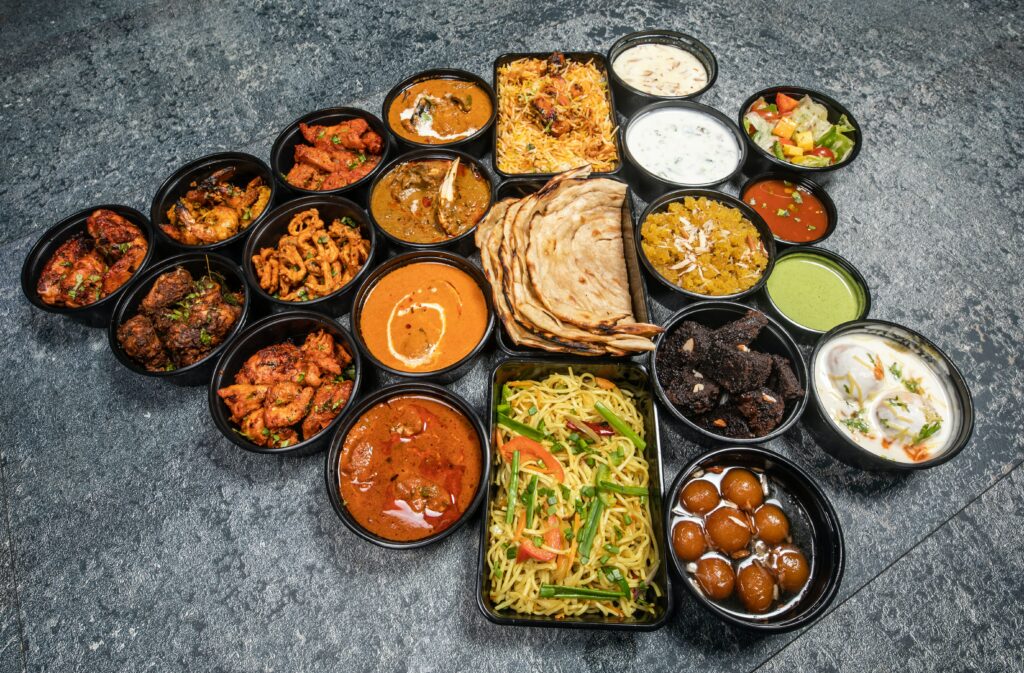 A feast of meat, vegetables, sauces, and bread laid out in black dishes