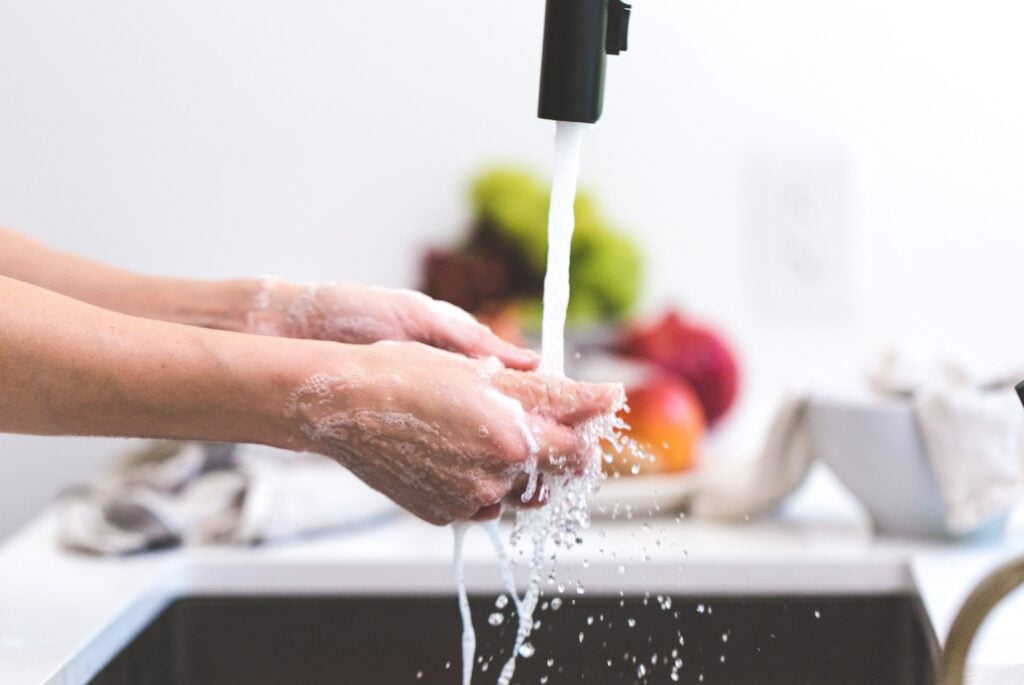 A person washing hands in the kitchen sink